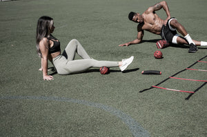 Two people exercising on a sports field with sports equipment. Roller-Peanut-Foam-COREFX 