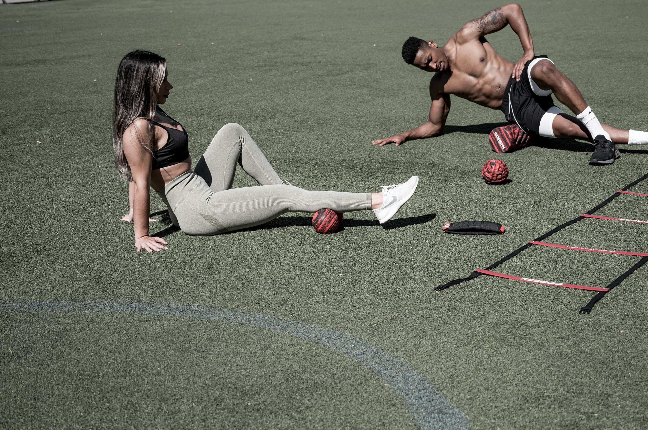 Two people exercising on a sports field with sports equipment. Roller-Peanut-Foam-COREFX 