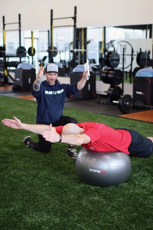 Two people exercising with a Corefit ball in a gym setting