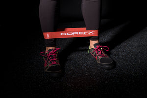 Person using a COREFX resistance band on a dark floor COREFX Pro Loop Resistance Band Set 4-Pack