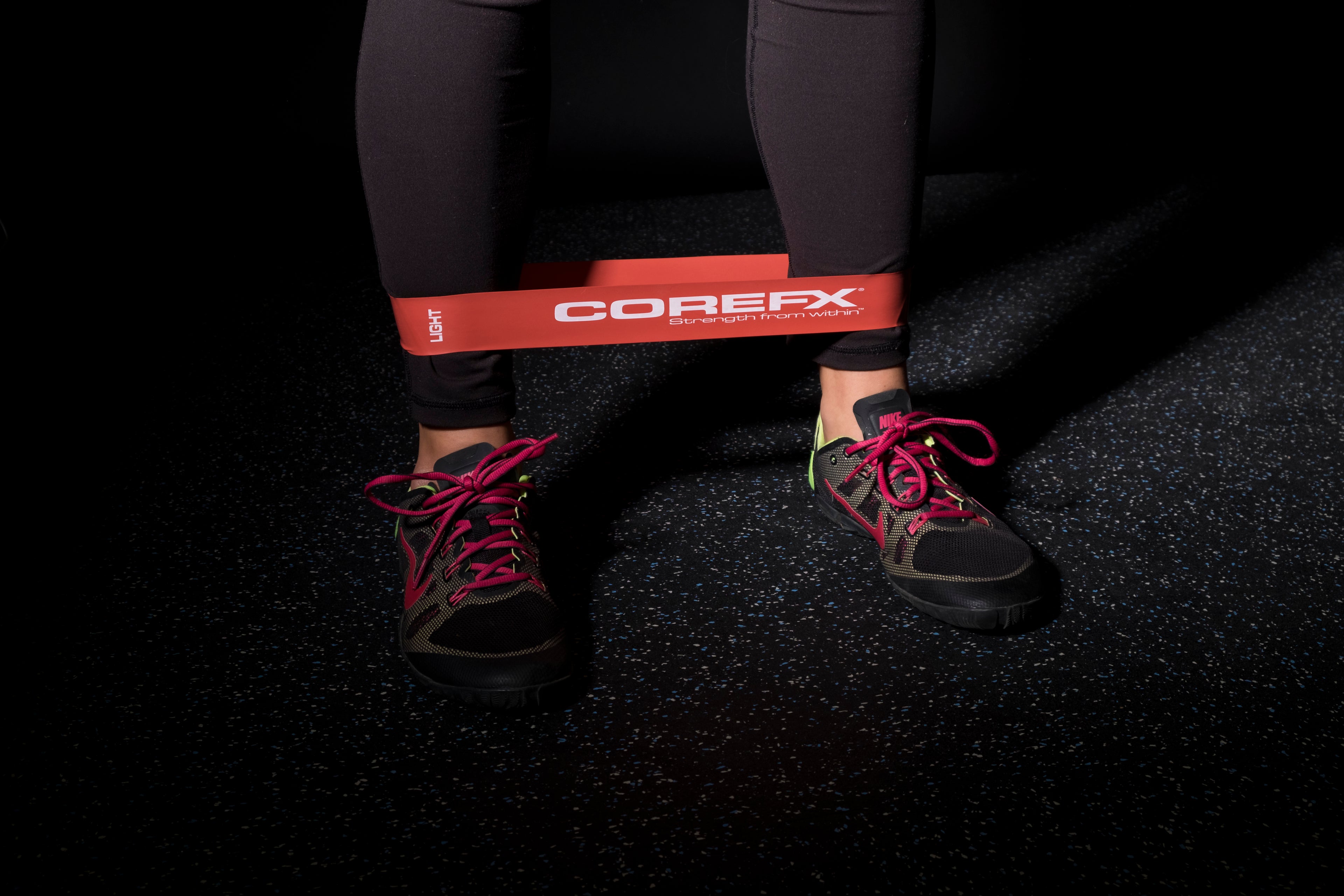 Person using a COREFX resistance band on a dark floor COREFX Pro Loop Resistance Band Set 4-Pack