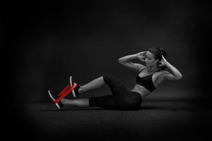 Woman exercising with resistance bands on a dark background COREFX Pro Loop Resistance Band Set 4-Pack