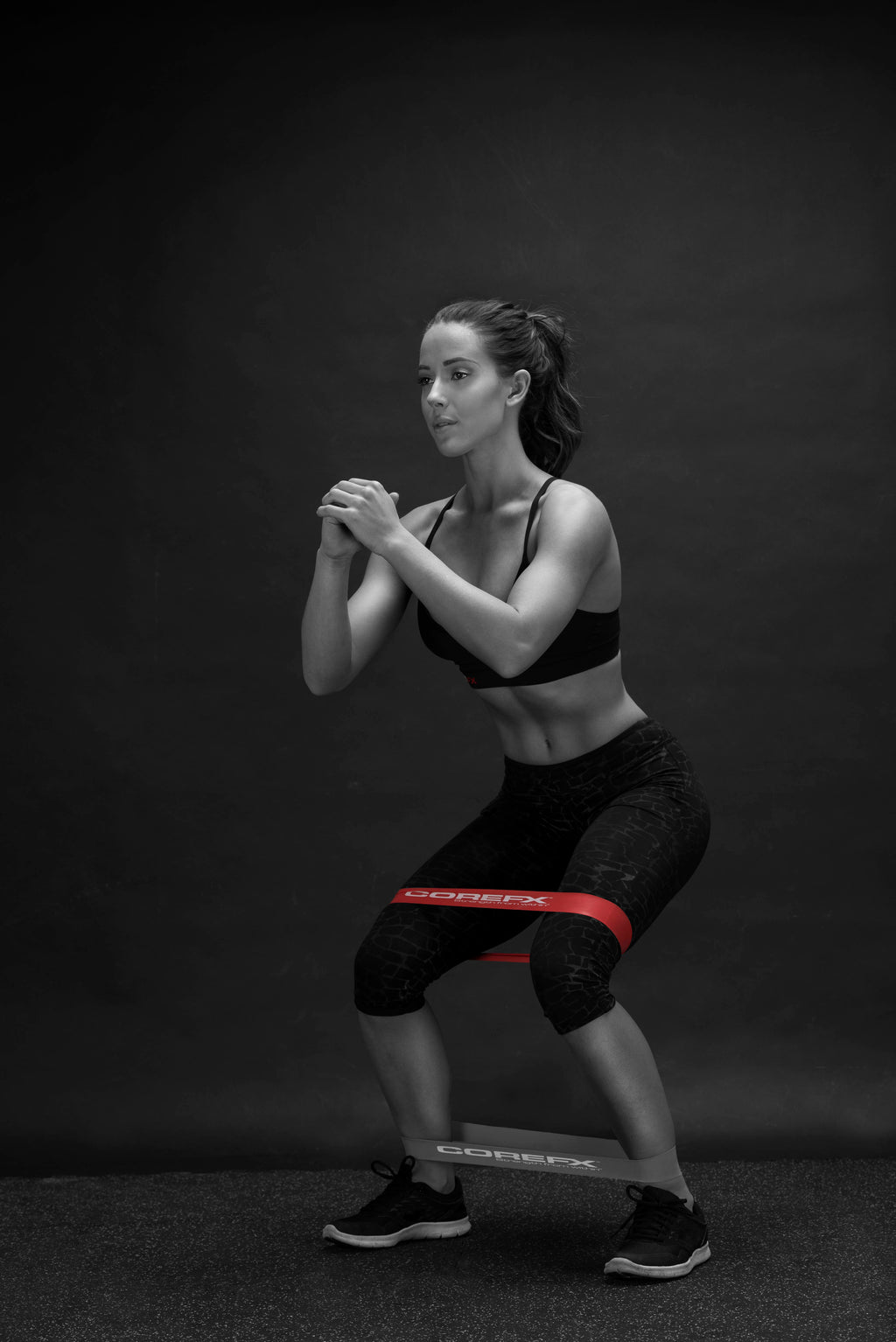 Woman performing a squat with a barbell on a dark background COREFX Pro Loop Resistance Band Set 4-Pack